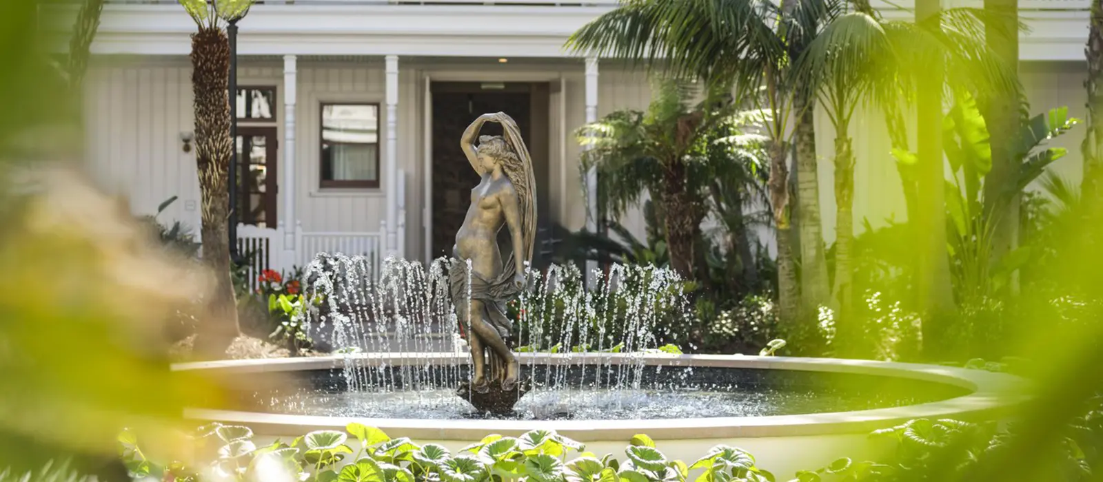 Bronze statue fountain surrounded by tropical landscaping in the garden courtyard of the historic Hotel del Coronado.