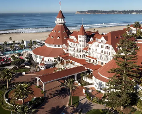 Hotel del Coronado, a historic Victorian-style resort with red-tiled roofs, palm trees, and ocean views on Coronado Island.